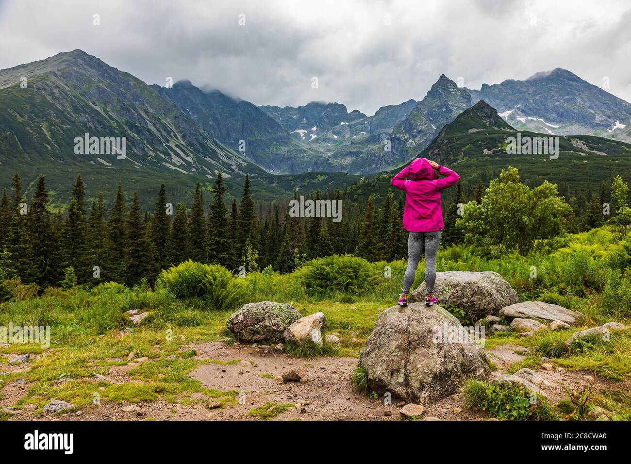 Mujer en el impermeable mirando el panorama de la montaña Tatra en la lluvia Foto de stock
