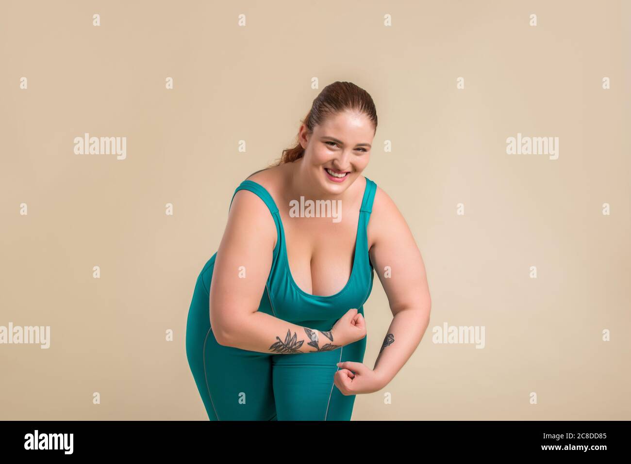 Mujer bastante grande llevando ropa deportiva posando en el estudio - hermosa chica aceptando la imperfección corporal, disparos de belleza en el estudio - conceptos sobre el cuerpo a Foto de stock