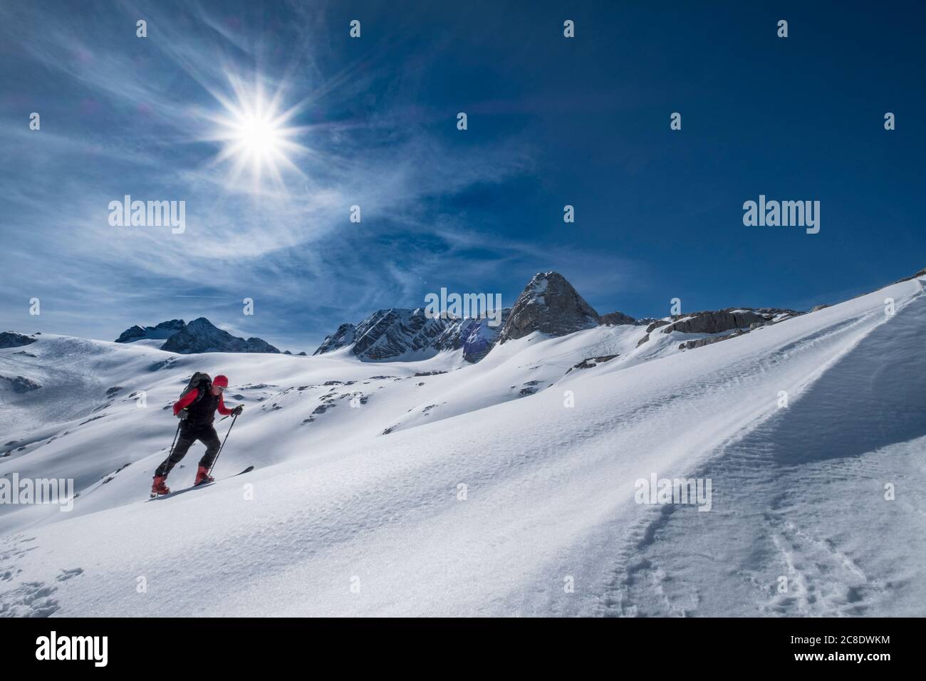 Hombre esquiando en la nieve cubrió la montaña Dachstein contra el cielo durante el día soleado, Austria Foto de stock