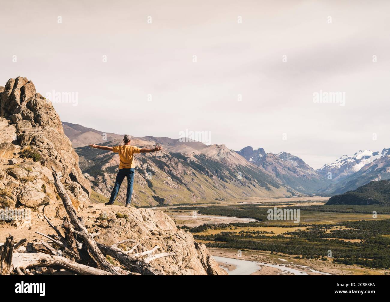 Hiker masculino con brazos estirados mirando a los Andes de la Patagonia mientras estaba parado en el rock, Argentina Foto de stock