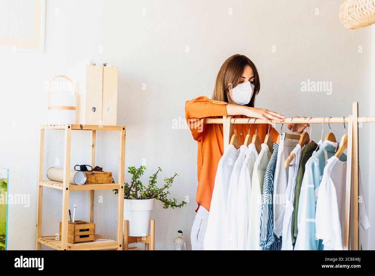 Diseñadora de moda femenina trabajando en casa con puesto de ropa  mascarilla protectora Fotografía de stock - Alamy