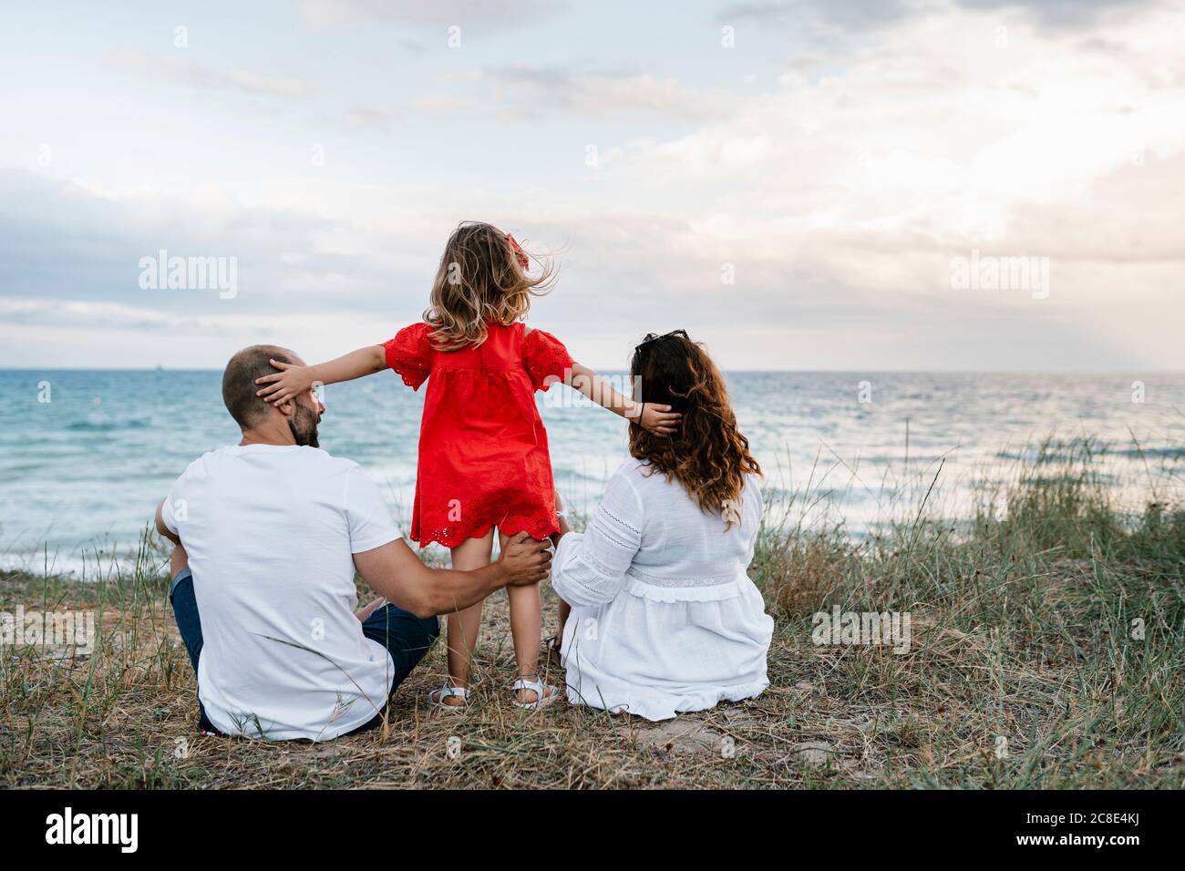 Familia pasando tiempo de calidad en la playa contra el cielo nublado Foto de stock