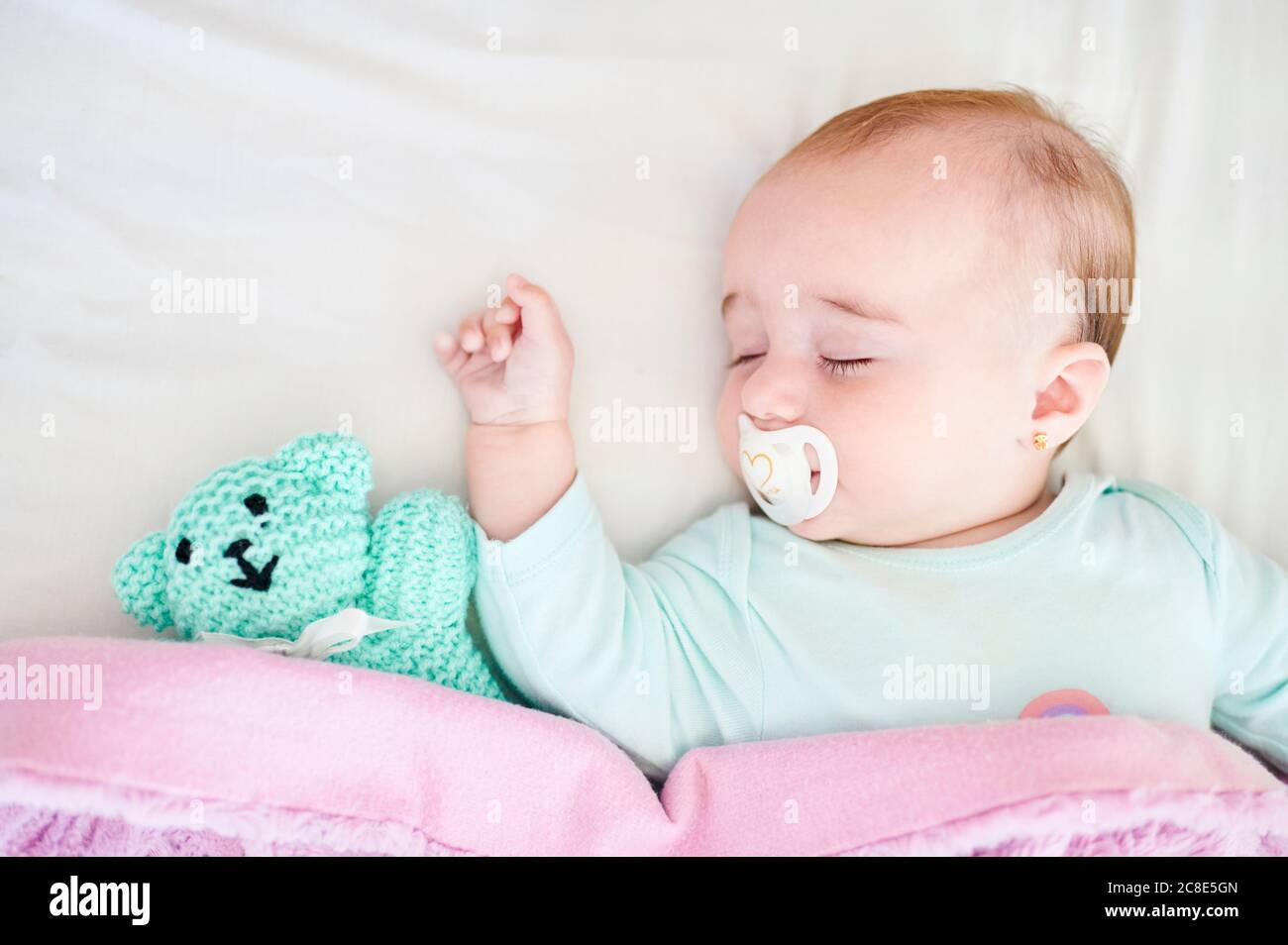 Bebé niña con chupete 0 3 meses vistiendo ropa bebé acostado en el pesebre  con su animal de peluche favorito Fotografía de stock - Alamy