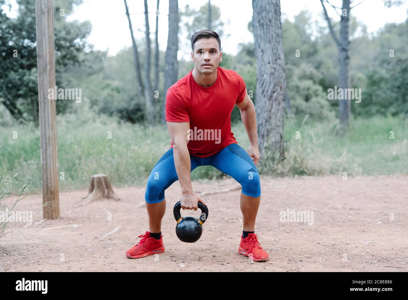 Joven atleta con mancuerna en el bosque Foto de stock