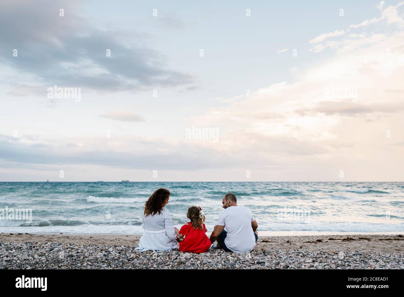 Familia pasando tiempo de calidad en la costa en la playa contra la turbia cielo Foto de stock