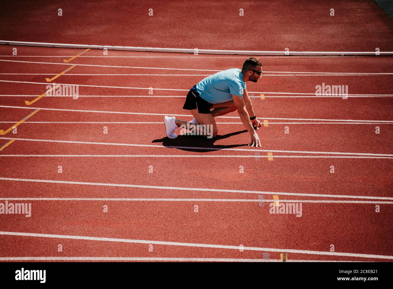 Atleta masculino en posición inicial en pista de tartan Foto de stock