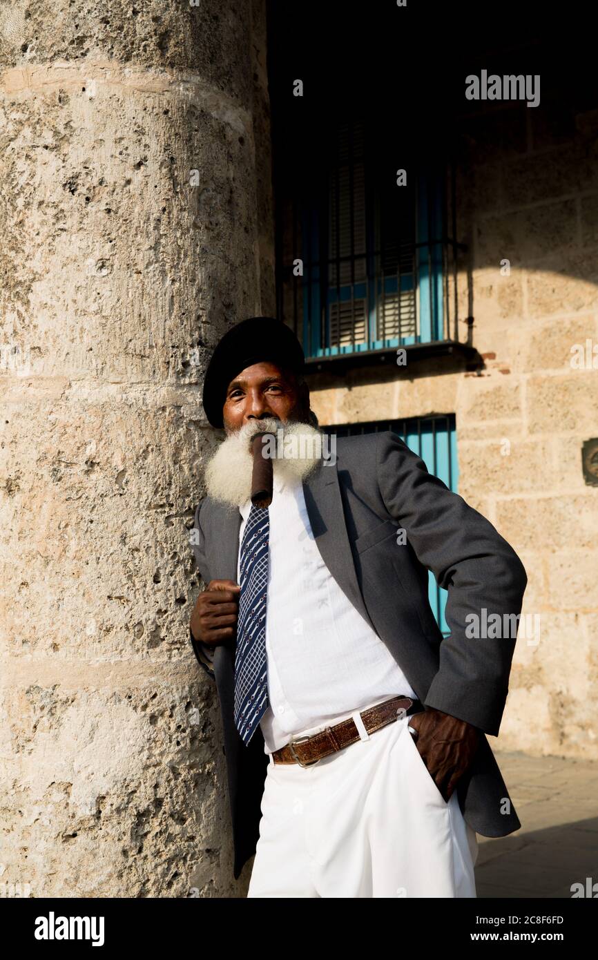 La Habana / Cuba - 04.16.2015: Hombre de edad afro cubano con una larga barba blanca con traje y una bereta militar negra, fumando un gran cigarro Foto de stock