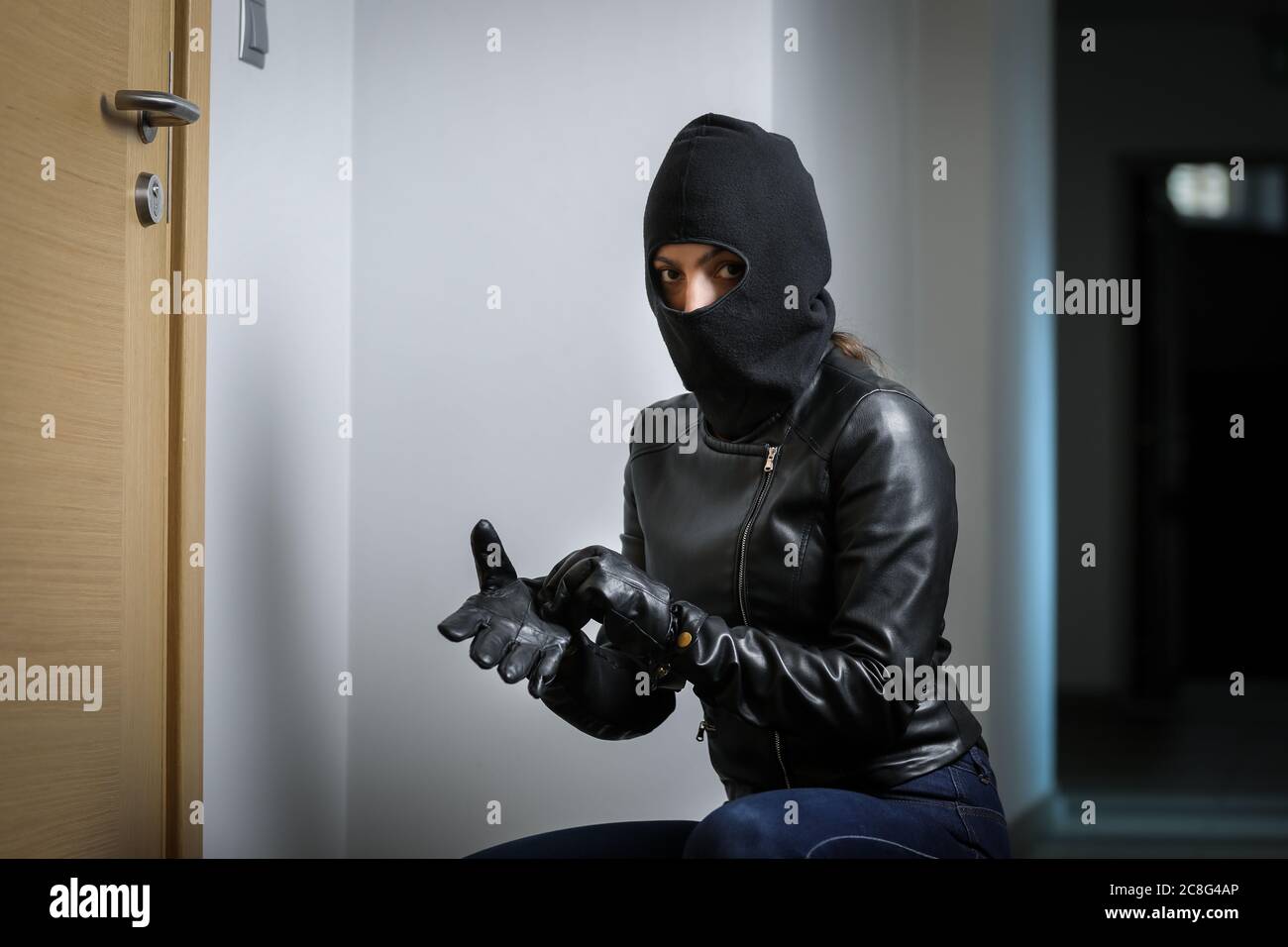 Ladrón se rompió en el apartamento. Robo de casa por mujer en una chaqueta  negra y máscara negra. Robo en una máscara. Ladrón en una máscara tratando  de romper Fotografía de stock -
