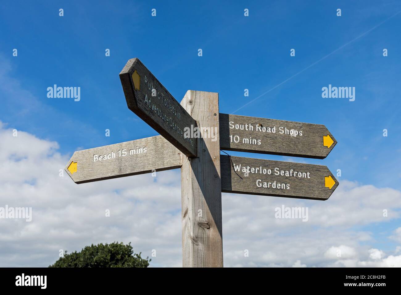 Una señal de madera que indica la dirección de la playa, tiendas de la carretera del sur, jardines del paseo marítimo de Waterloo y centro de aventura - Waterloo, Liverpool, Merseyside, Reino Unido Foto de stock