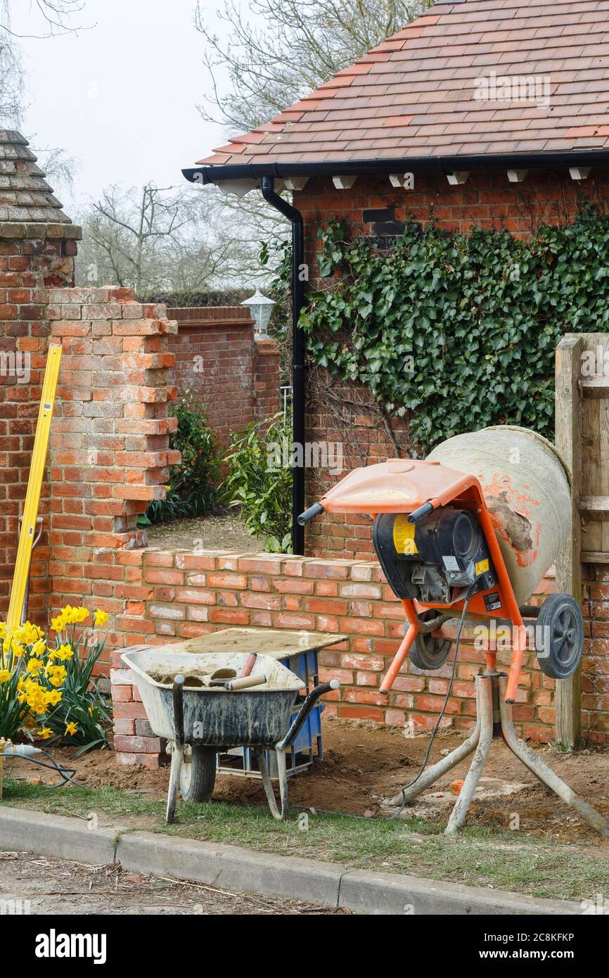 Construcción de una casa, una pared de ladrillo jardín con mezclador de cemento en el Reino Unido Foto de stock