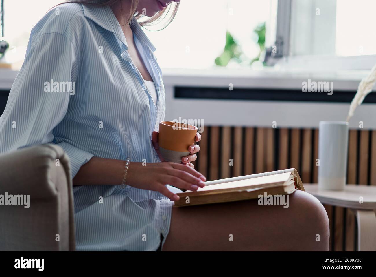 Hermosa chica leyendo un libro en casa. Ocio en el interior Foto de stock