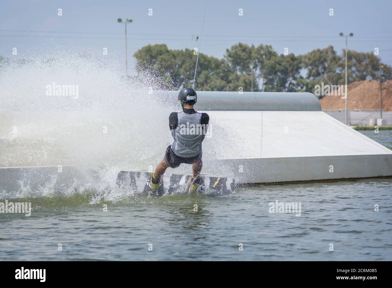 Hombre disfrutando de una actividad de wakeboard: Un deporte acuático en el que el jinete de pie en una tabla corta y tirado por un sistema de cables para realizar aer Foto de stock