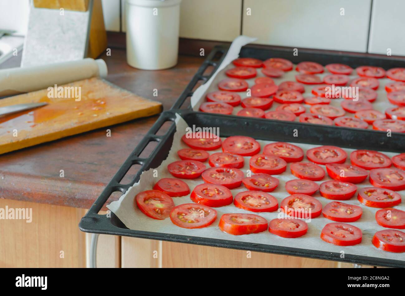 Dos bandejas de hornear con tomates picados en la mesa de la cocina. El  proceso de secado de verduras maduras en el horno. Comida casera seca  Fotografía de stock - Alamy