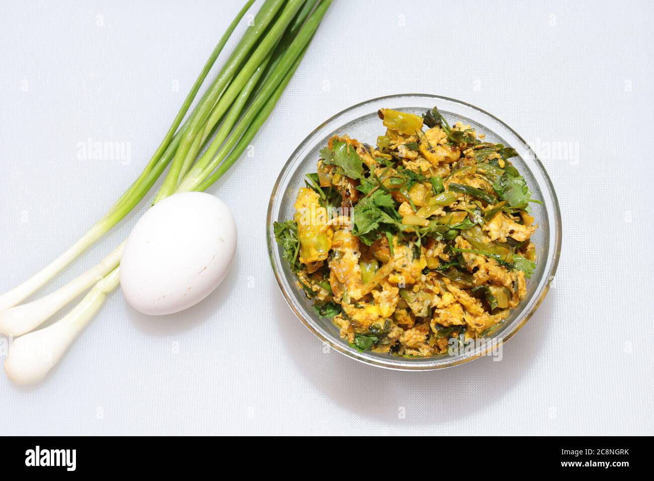 Raíces frescas de cebolla verde primavera con curry de huevo sobre un fondo blanco aislado Foto de stock