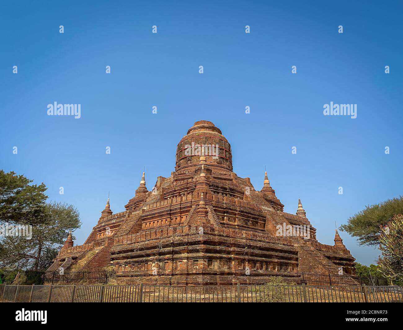 Antigua Pagoda Mingalazedi, o la "Stupa bendición" en el Viejo Bagan, Myanmar. Stupa en forma de pirámide en paisaje arbolado con fondo azul cielo Foto de stock