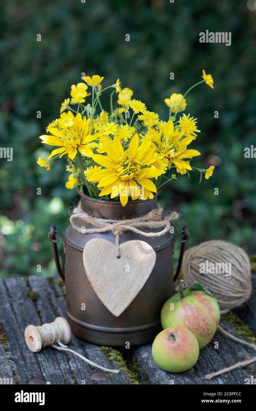 ramo rústico en amarillo de rudbeckia y flores de buttercup en lata de leche de cosecha Foto de stock