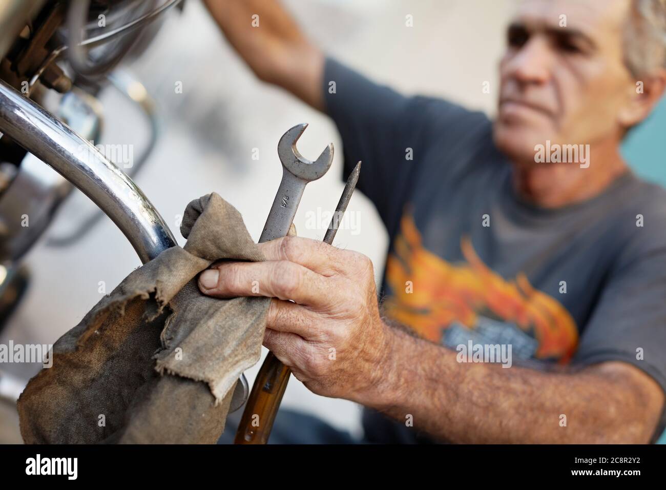 Senior Man examinando su motocicleta y el motor de fijación Foto de stock