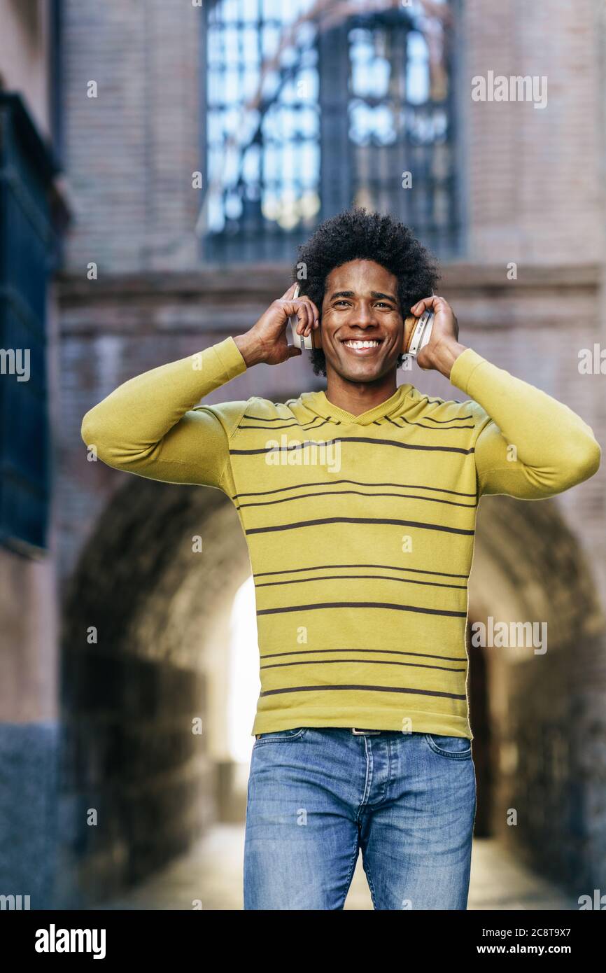 Hombre negro escuchando música con los auriculares inalámbricos de visita turística en Granada Foto de stock