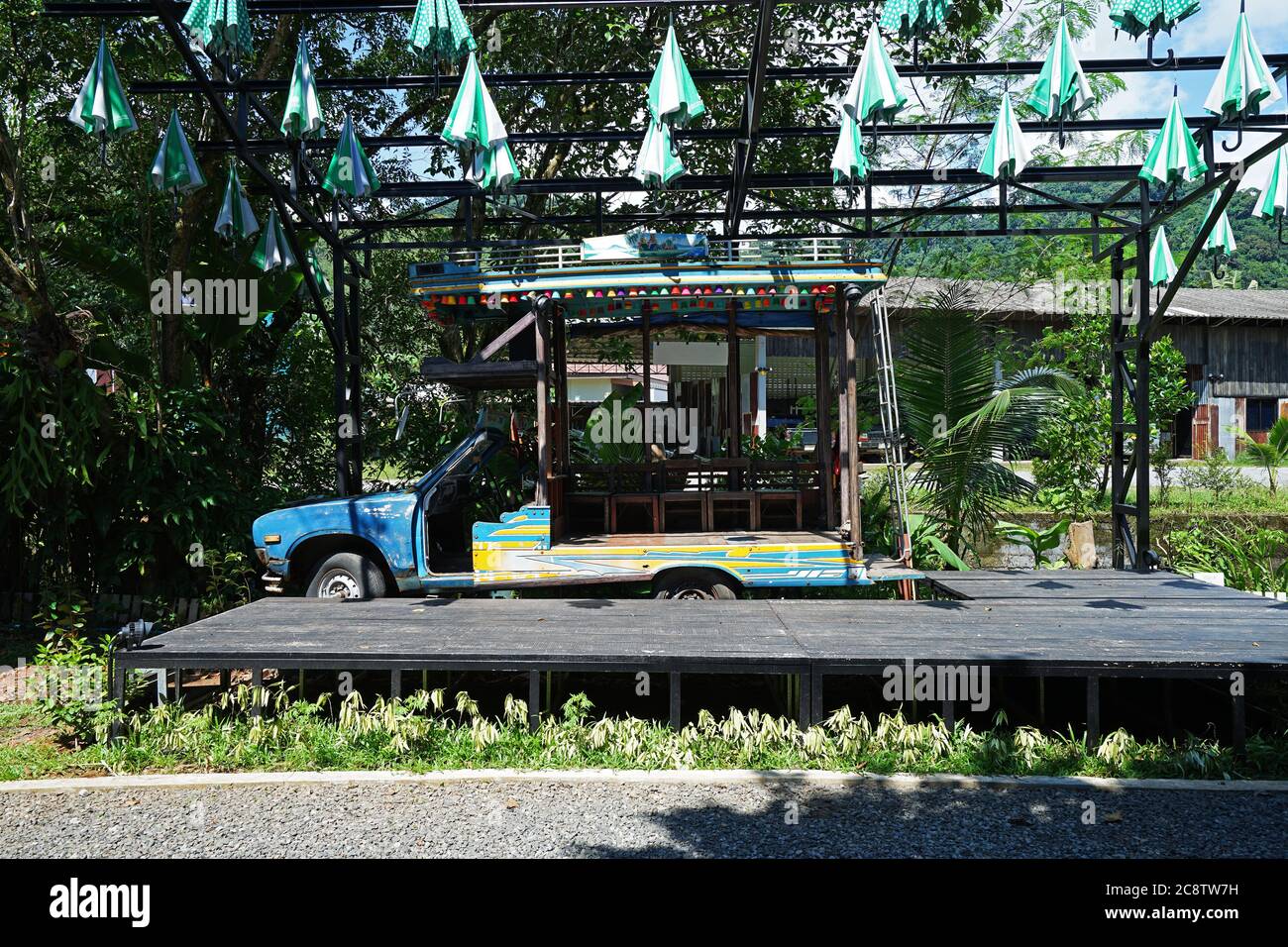 Antiguo escenario de madera en el restaurante local y café decorado con muebles de época, paraguas de colores y clásico carro de camiones - Phang Nga, Tailandia Foto de stock