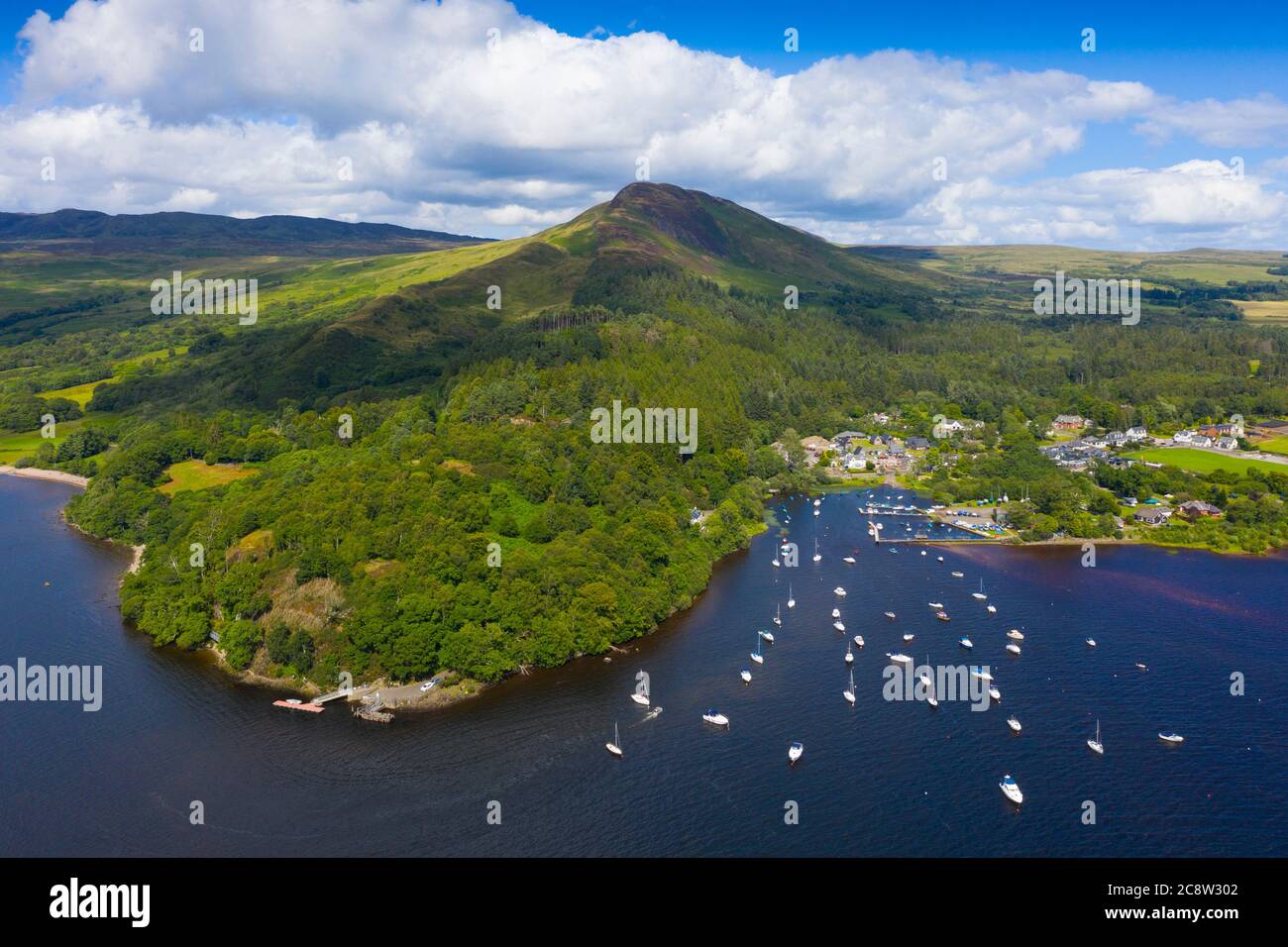 Vista aérea del pueblo de Balmaha y la colina Conic en las orillas del lago Lomond en el lago Lomond y el Parque Nacional Trossachs, Escocia, Reino Unido Foto de stock