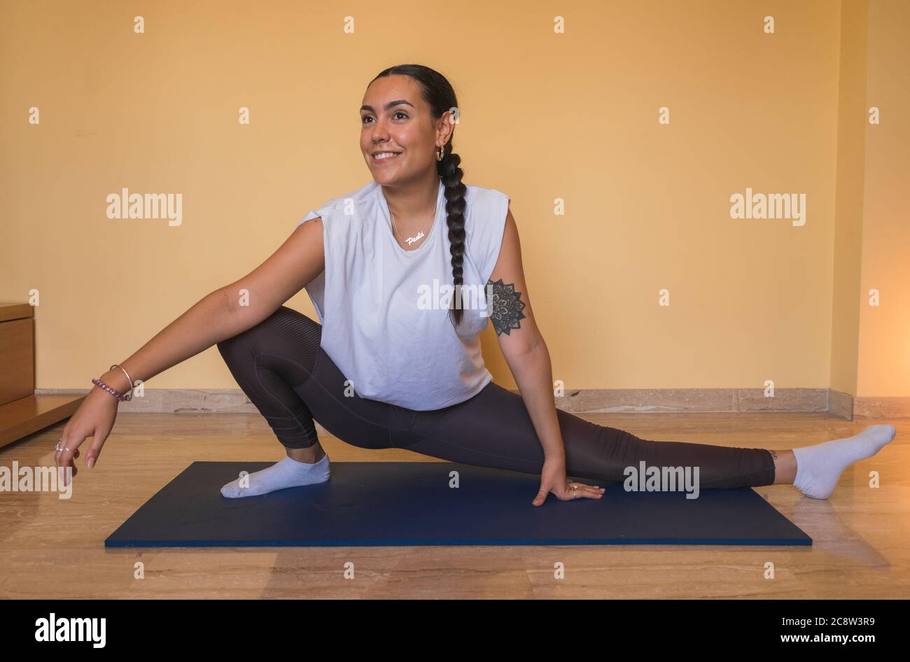 Mujer deportiva atractiva con ropa deportiva blanca usando bloques de yoga  mientras hace tablones laterales en la alfombra de yoga. yoga en casa.