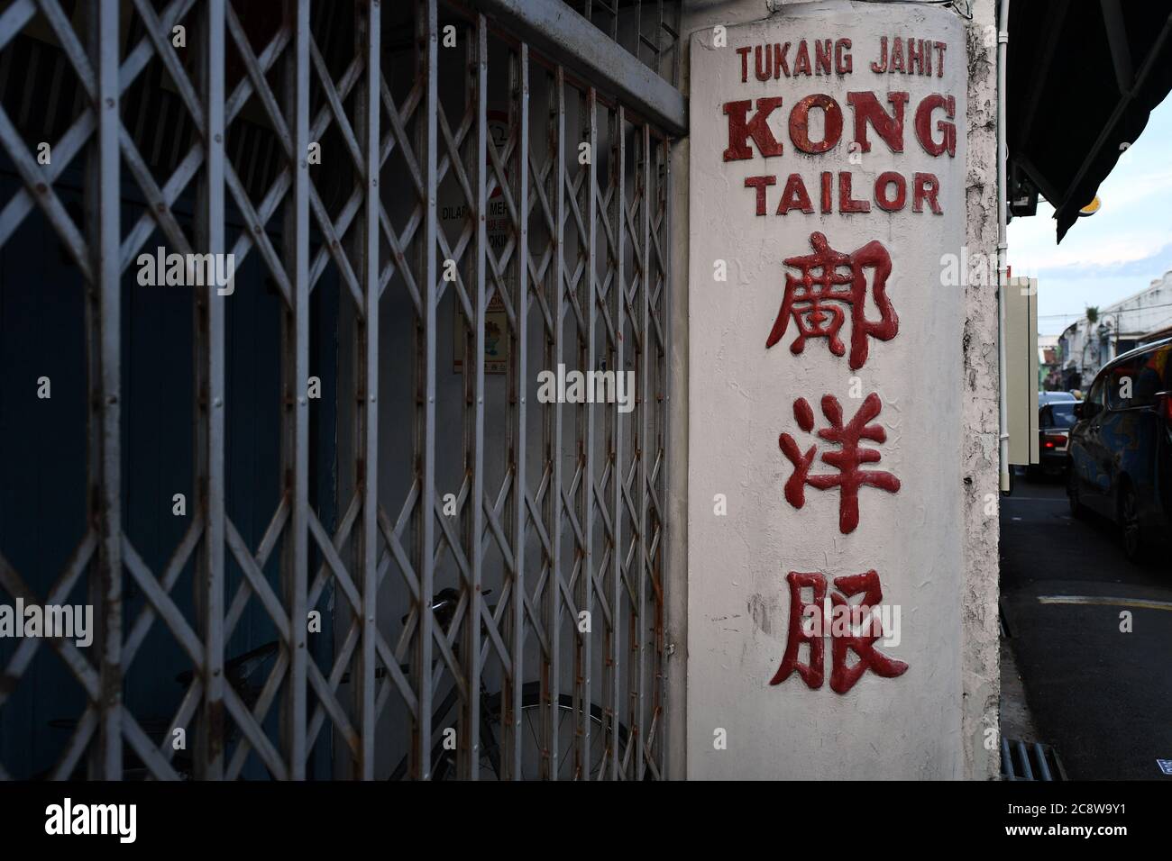 Una antigua tienda de sastre con escritura China y occidental está cerrada por el día en Malacca Malasia Foto de stock