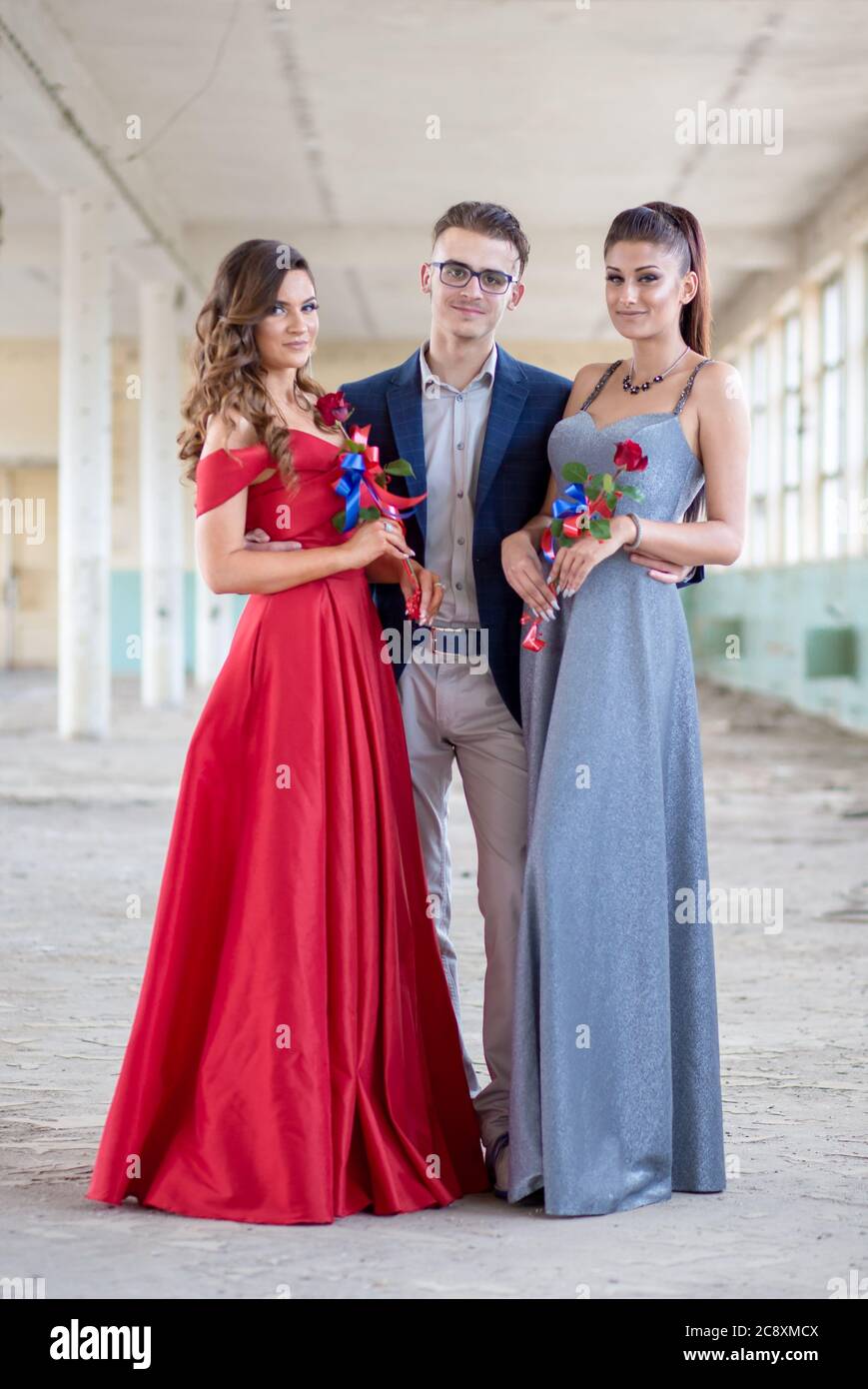 Guapo chico en traje azul con dos hermosas chicas en vestidos glamorosos.  Listo para su noche de prom Fotografía de stock - Alamy