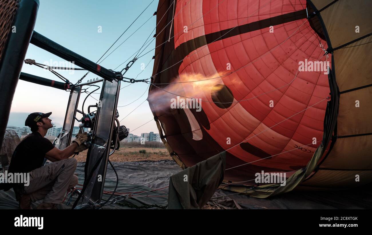 El piloto está calentando los quemadores de un globo inflable de aire caliente, minutos antes de despegar, Afula, Israel. Foto de stock