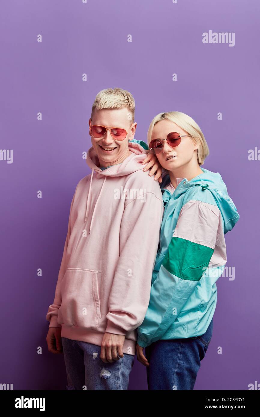 Pareja joven satisfecho en ropa de moda al aire libre mirar la cámara con  un aspecto seguro, tener buenas relaciones, estar junto a la otra en  púrpura Fotografía de stock - Alamy