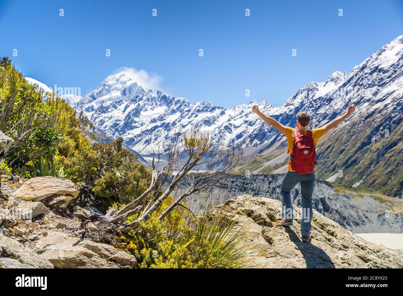 New Zealand hiker viajes naturaleza senderismo hombre ganar con los brazos para arriba en el éxito. Aventura al aire libre pisoteando a los mochileros animando a la vista del Monte Cook Foto de stock