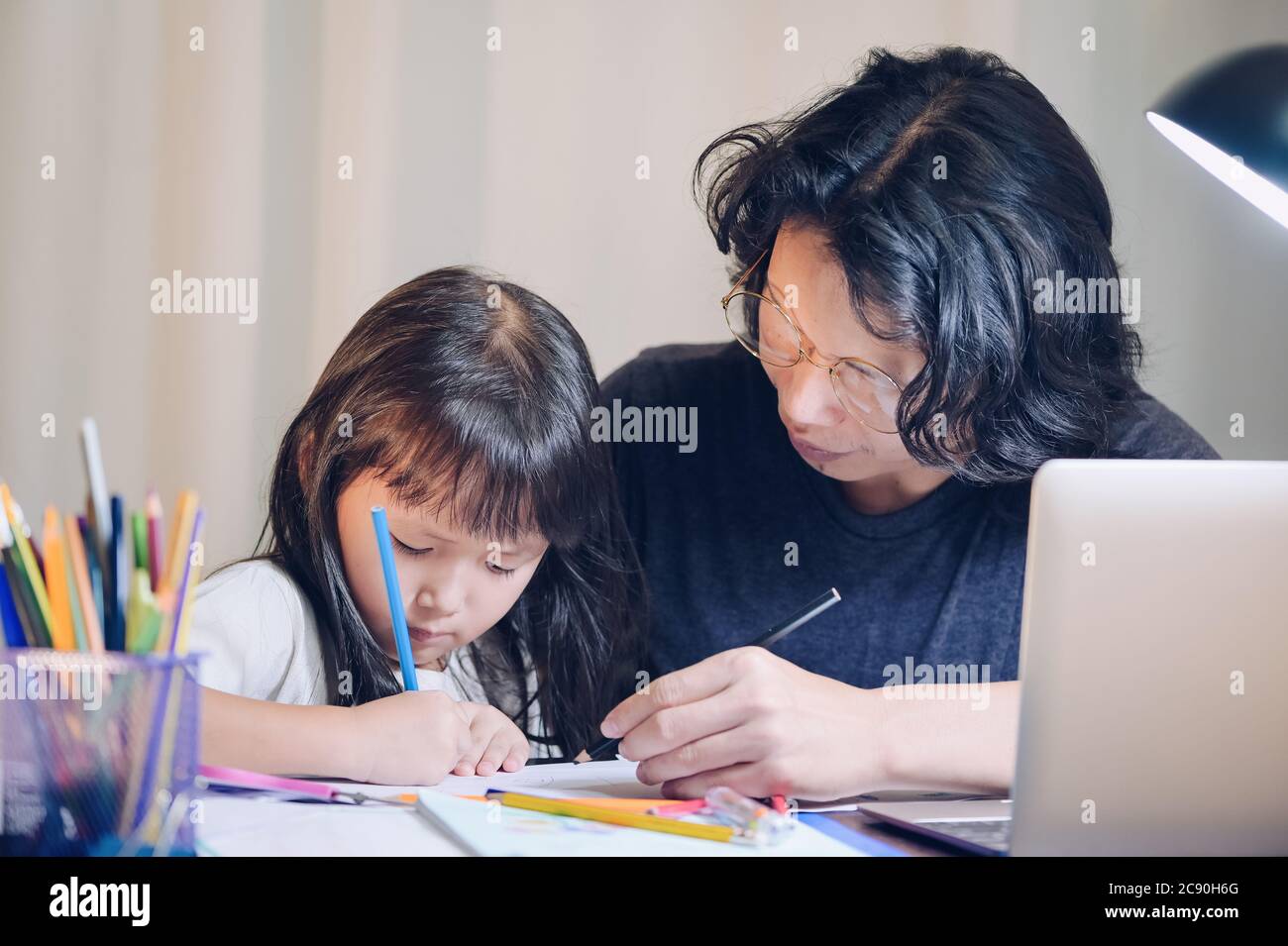 Concepto de escuela en casa, el padre enseña a la hija a niños asiáticos  haciendo la tarea escolar y su ordenador portátil hacer horas extras en la  mesa de trabajo en casa