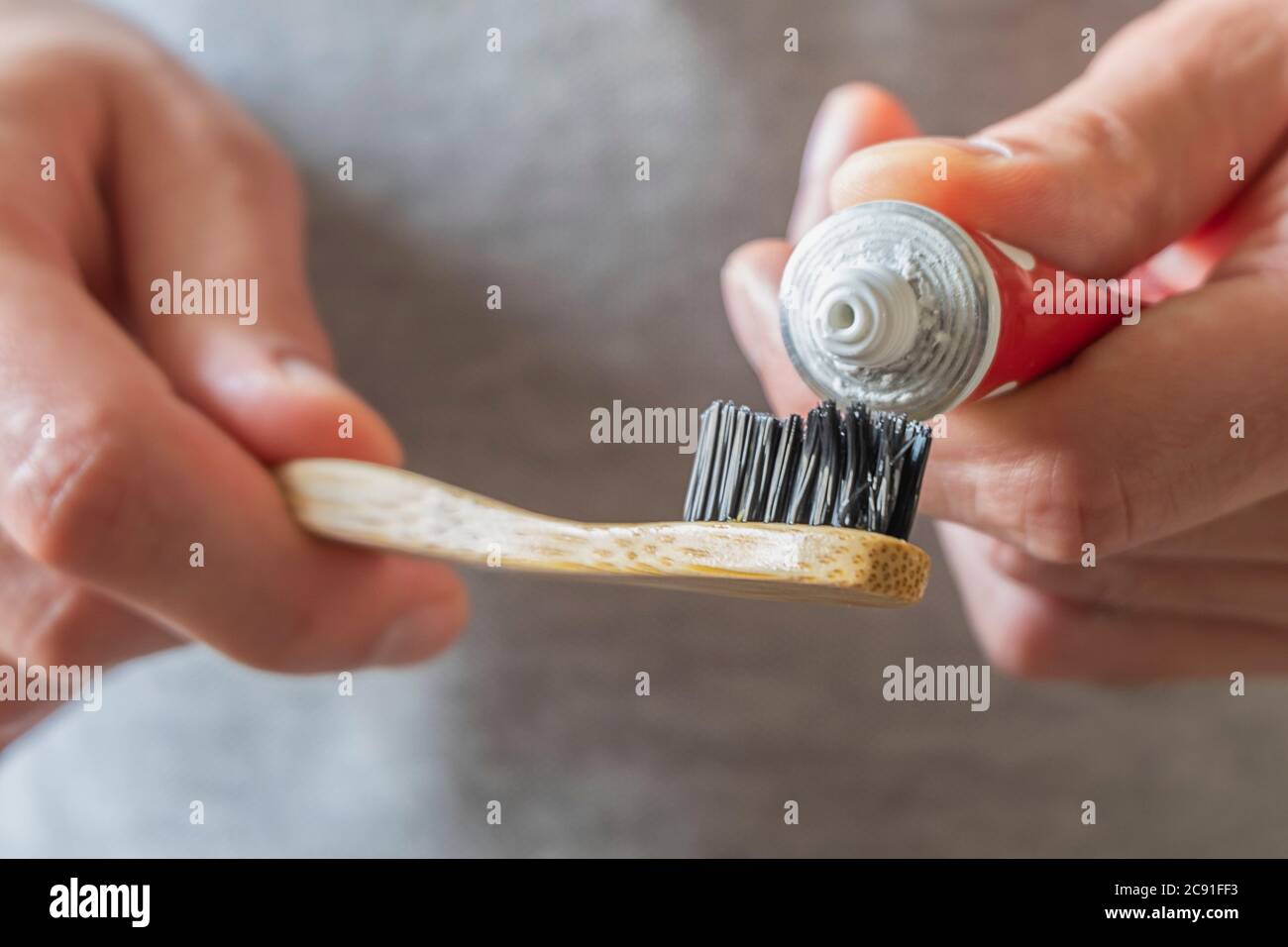 Manos masculinas aplicando pasta dental en un cepillo de dientes de bambú natural ecológico. Cero residuos en casa, artículos sin plástico Foto de stock
