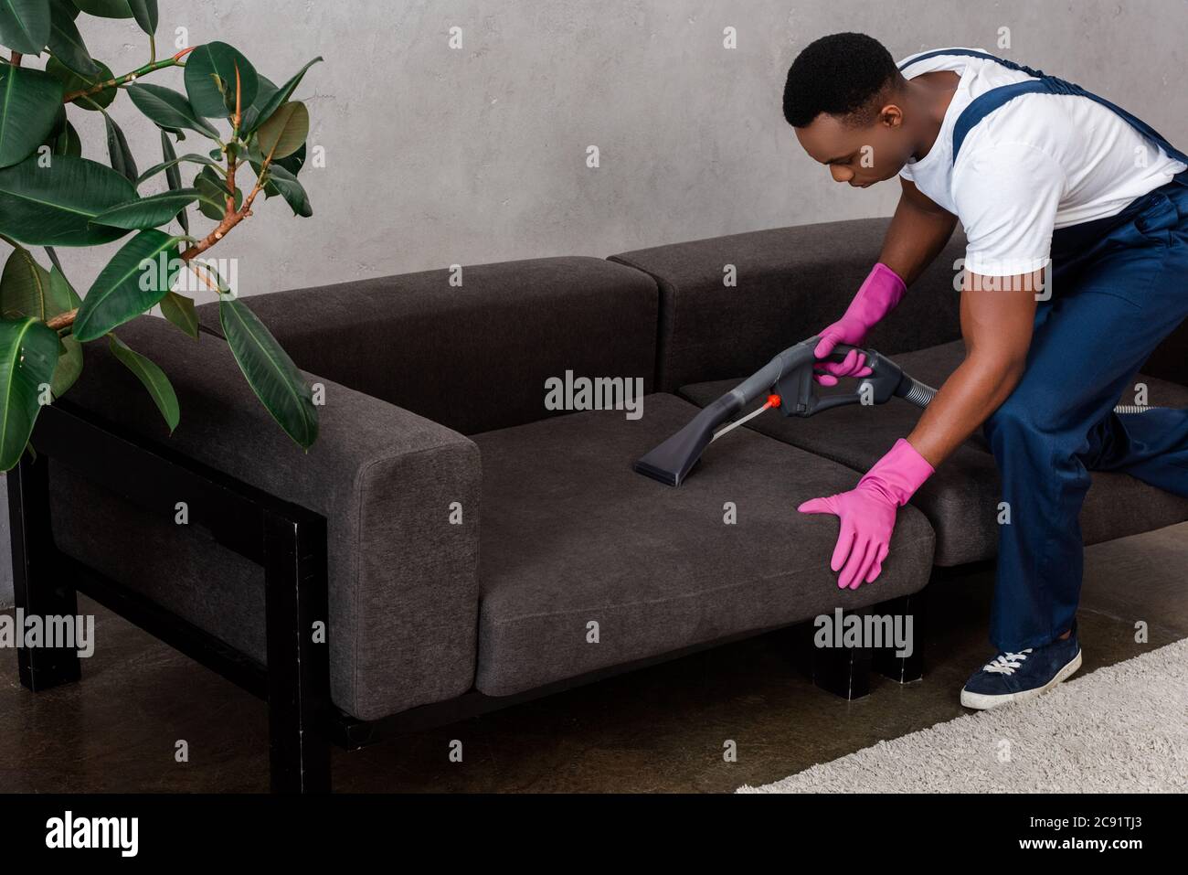 Enfoque selectivo de limpiador afroamericano en la tapicería de limpieza  uniforme de sofá en casa Fotografía de stock - Alamy