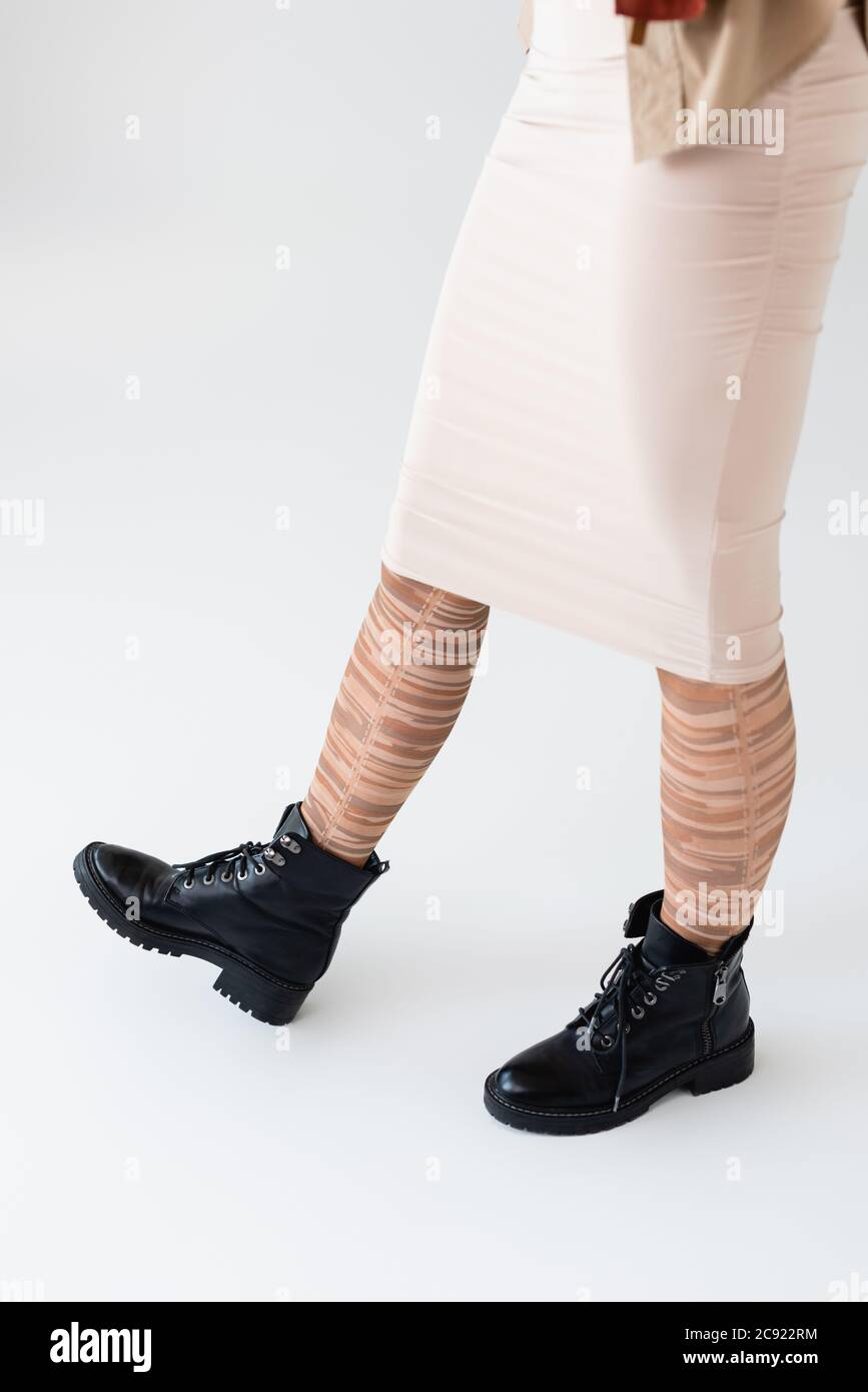 vista recortada de la chica en elegantes medias a rayas y botas negras en  blanco Fotografía de stock - Alamy