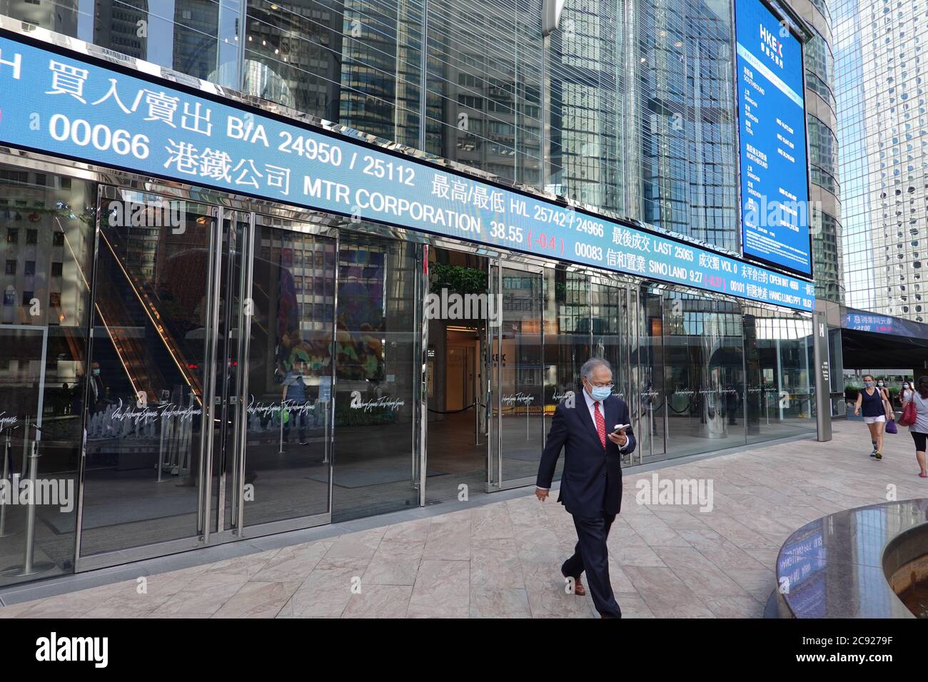 Un hombre de negocios pasó por la bolsa de Hong Kong, con un ticker  mostrando los precios de las acciones - fuera de la Bolsa de Hong Kong  Limited Fotografía de stock -