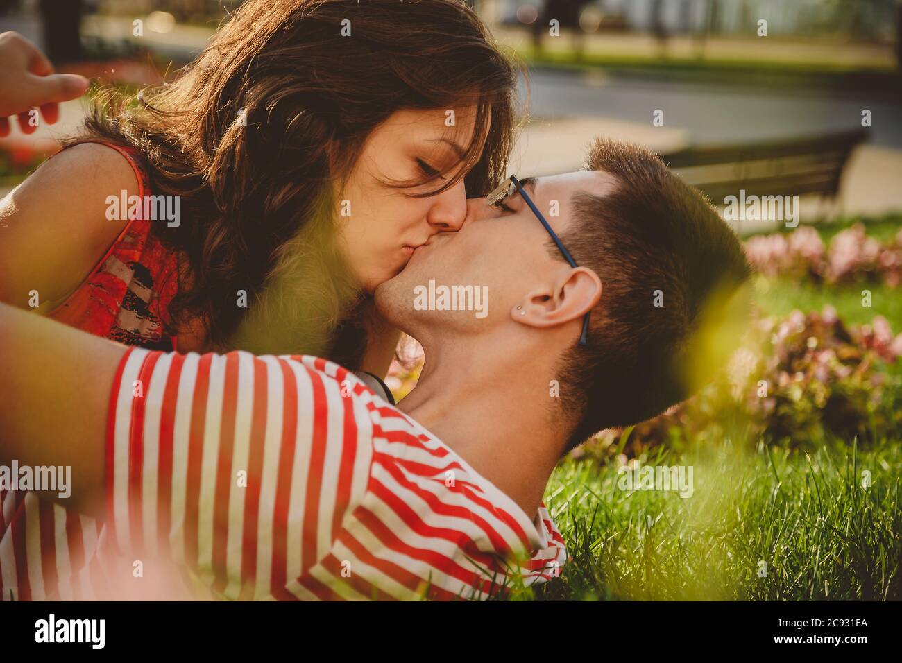 Cerca de una pareja encantadora tumbada en césped verde en el parque, besando y pasando tiempo juntos Foto de stock