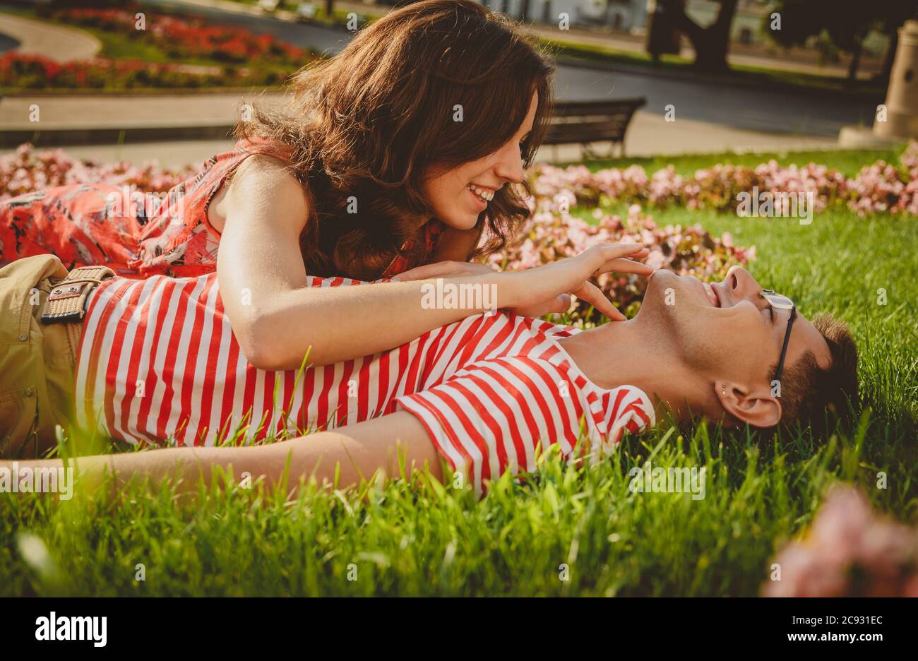 Una pareja elegante y moderna tumbada en el césped en el parque y pasar tiempo juntos Foto de stock