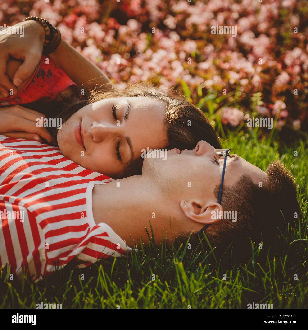Cerca de una pareja linda tumbada en césped verde en el parque y pasar tiempo juntos Foto de stock