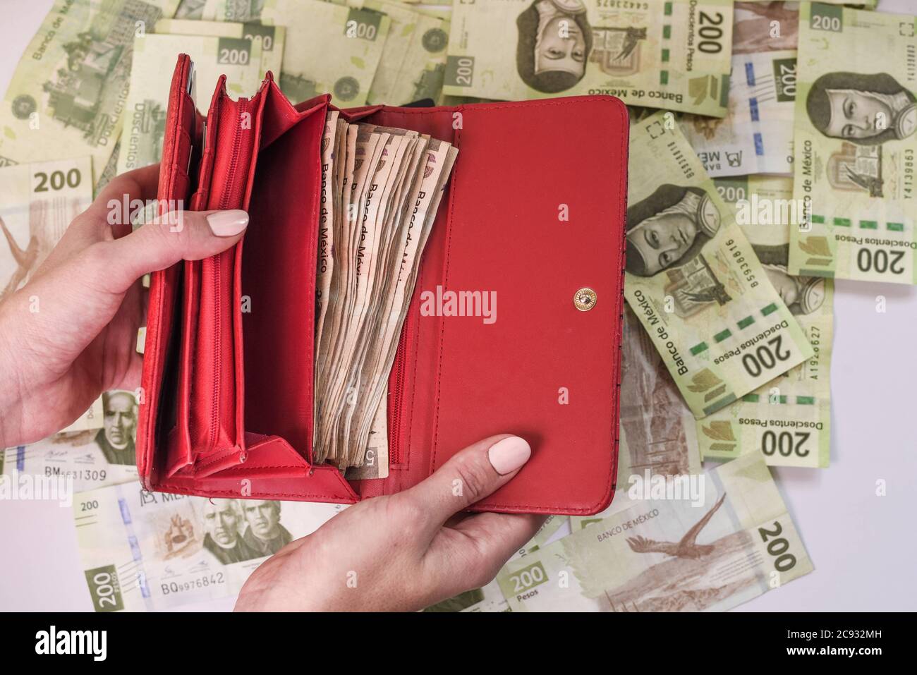 Disparo de cabeza de manos femeninas abriendo una cartera roja con dinero  encima de un montón de pesos coloridos Fotografía de stock - Alamy