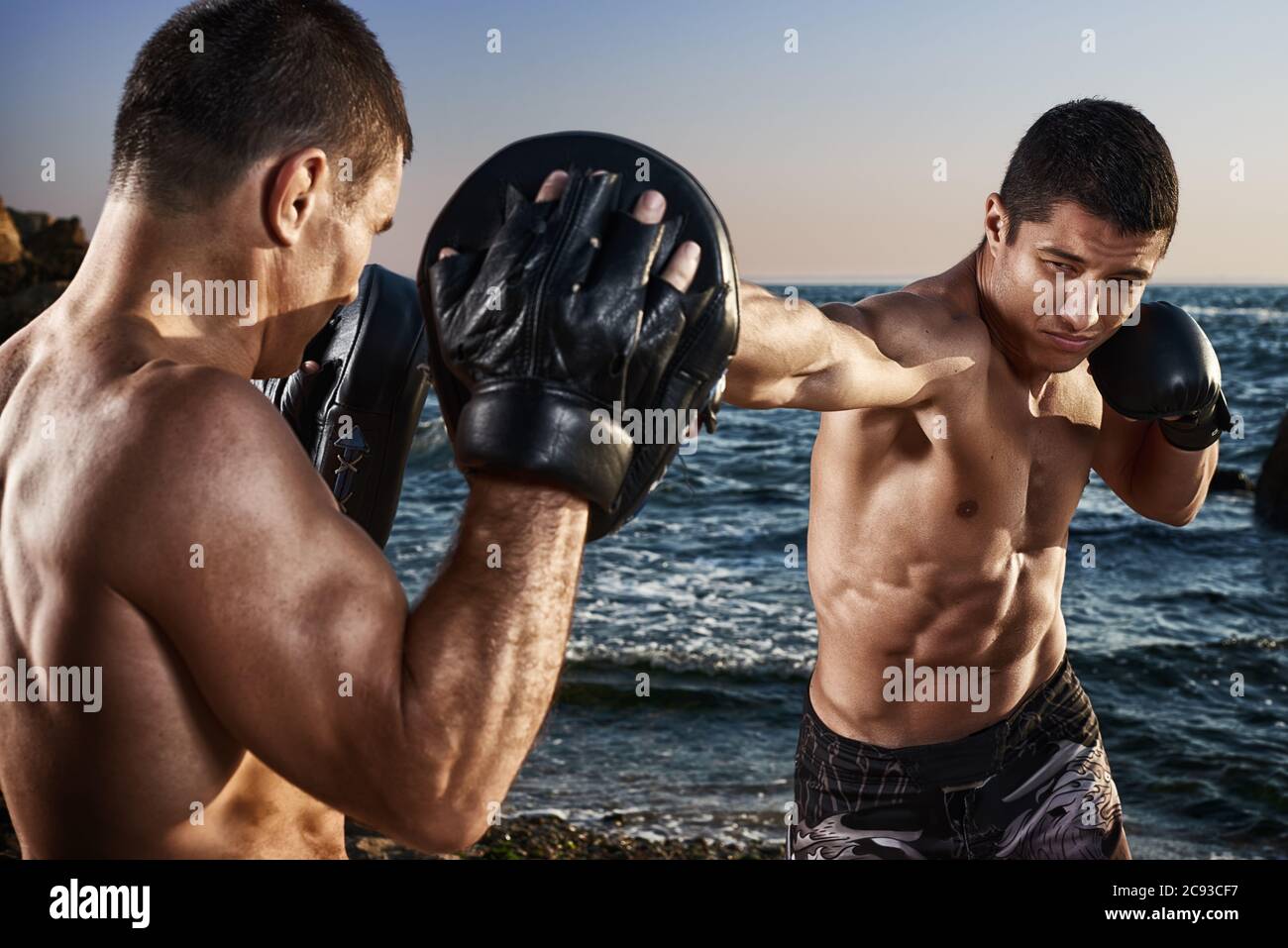 Fighter está entrenando sus habilidades de boxeo con un entrenador.  Entrenamiento al aire libre en una playa. Boxeo, mma, lucha libre, karate.  Atleta joven, fuerte y musculoso Fotografía de stock - Alamy