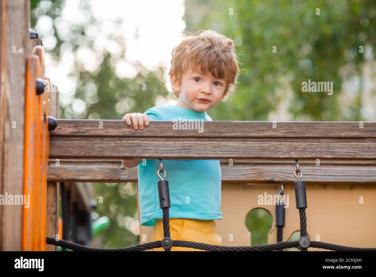 un niño de dos años juega en un pueblo para niños en el verano. Estilo de vida de los niños Foto de stock