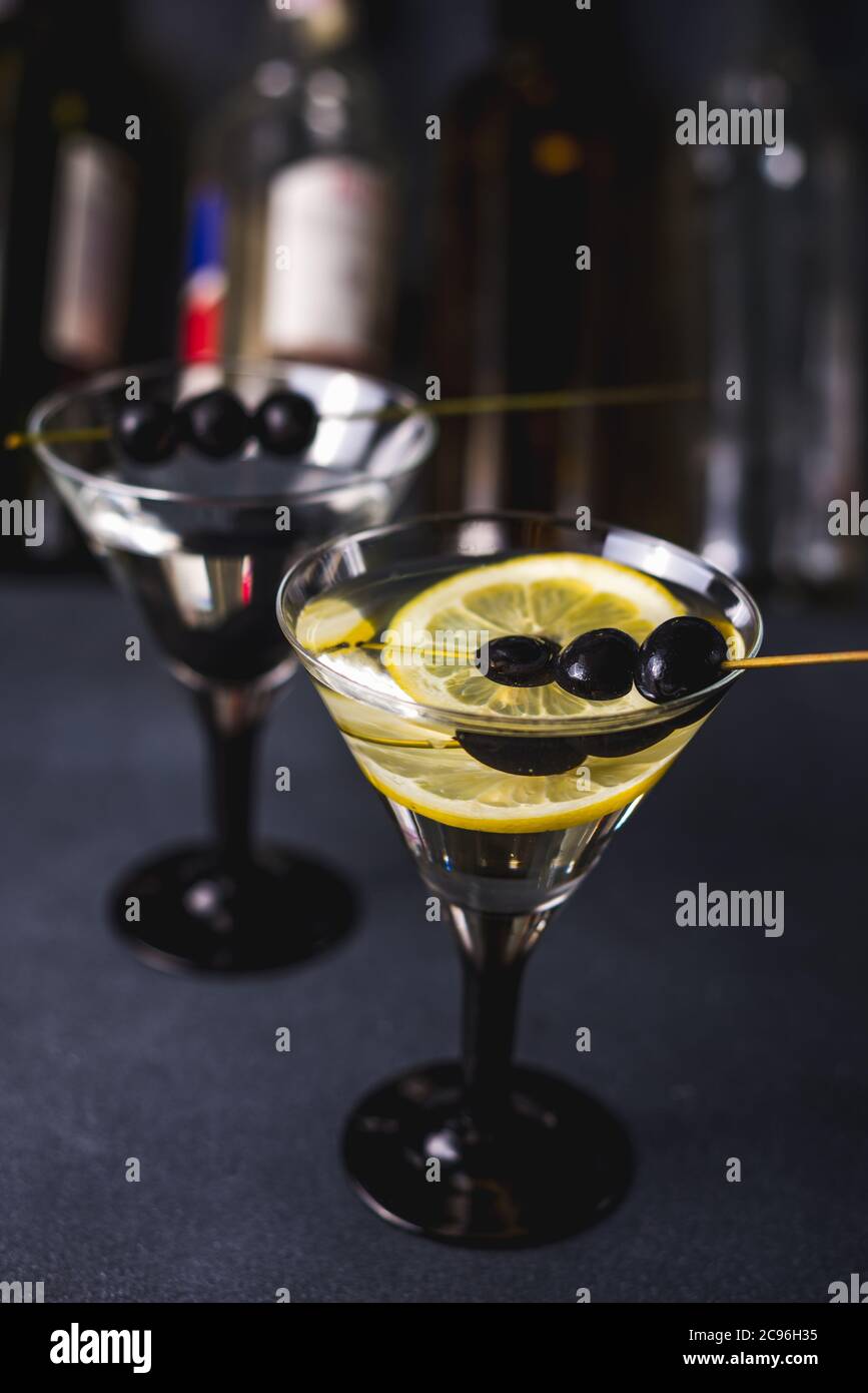 Cóctel de alcohol con salpicadura. Martini seco con aceitunas negras. Cóctel Vermouth dentro de vidrio martini sobre fondo oscuro. Copas de Martini en el bar. Foto de stock