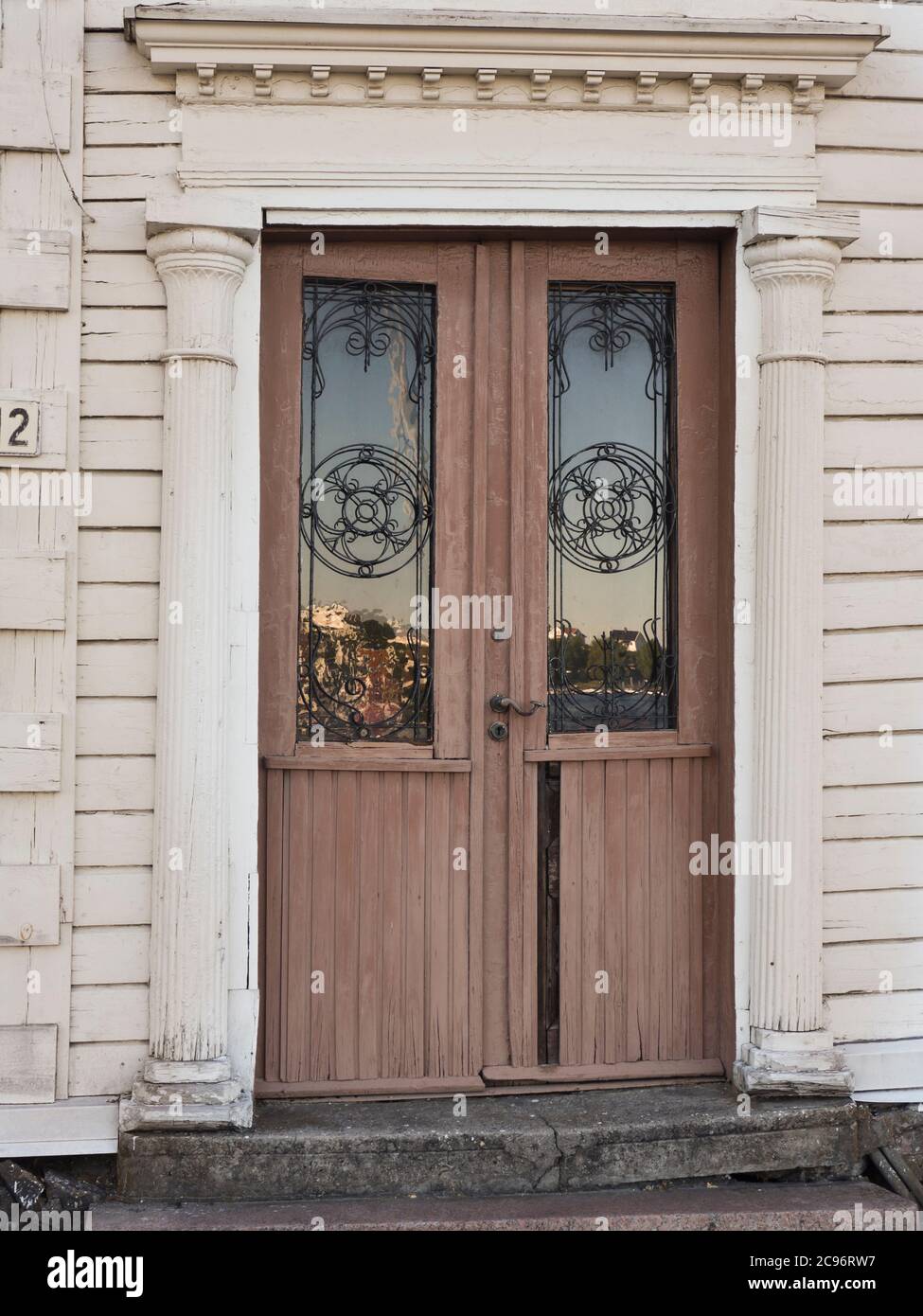 Detalle del edificio, antigua puerta marrón gastada con decoración art nouveau y columnas, número 2, en el puerto de Arendal Noruega Foto de stock