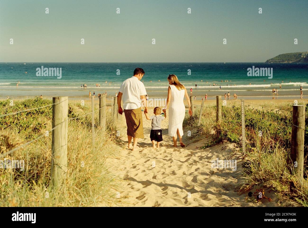 Una pareja lleva las manos de su joven en el camino de acceso a Freshwater Beach, Sydney Foto de stock