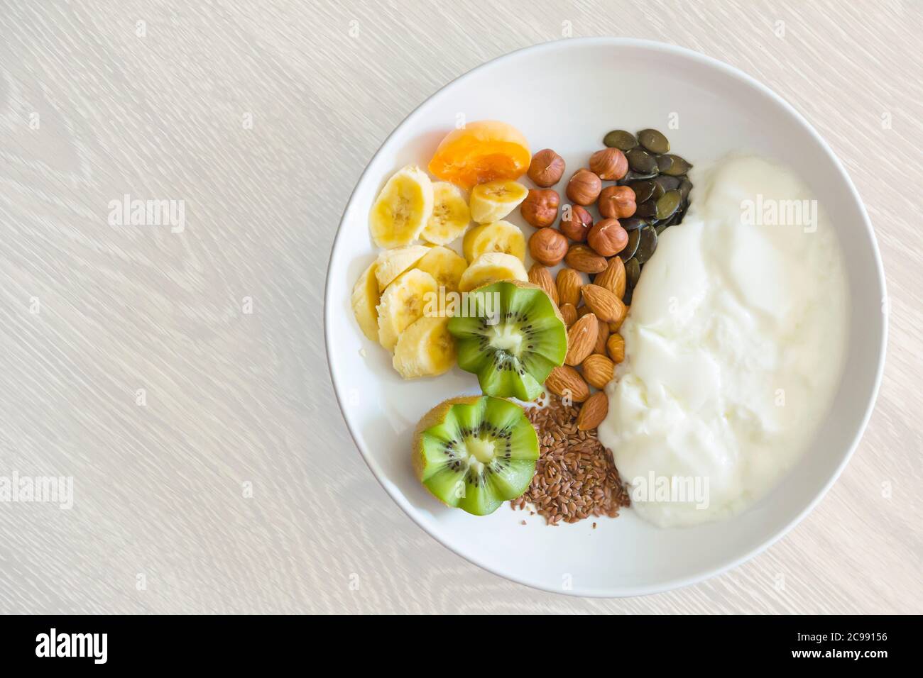 comida saludable - el desayuno consiste en yogur, nueces, semillas y frutas frescas Foto de stock
