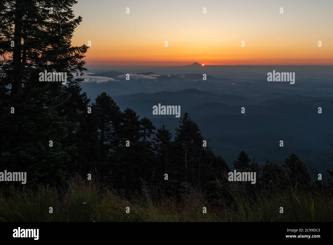 El amanecer está justo sobre el flanco sur del Monte Hood, con el bosque y el valle Willamette en primer plano. Foto de stock
