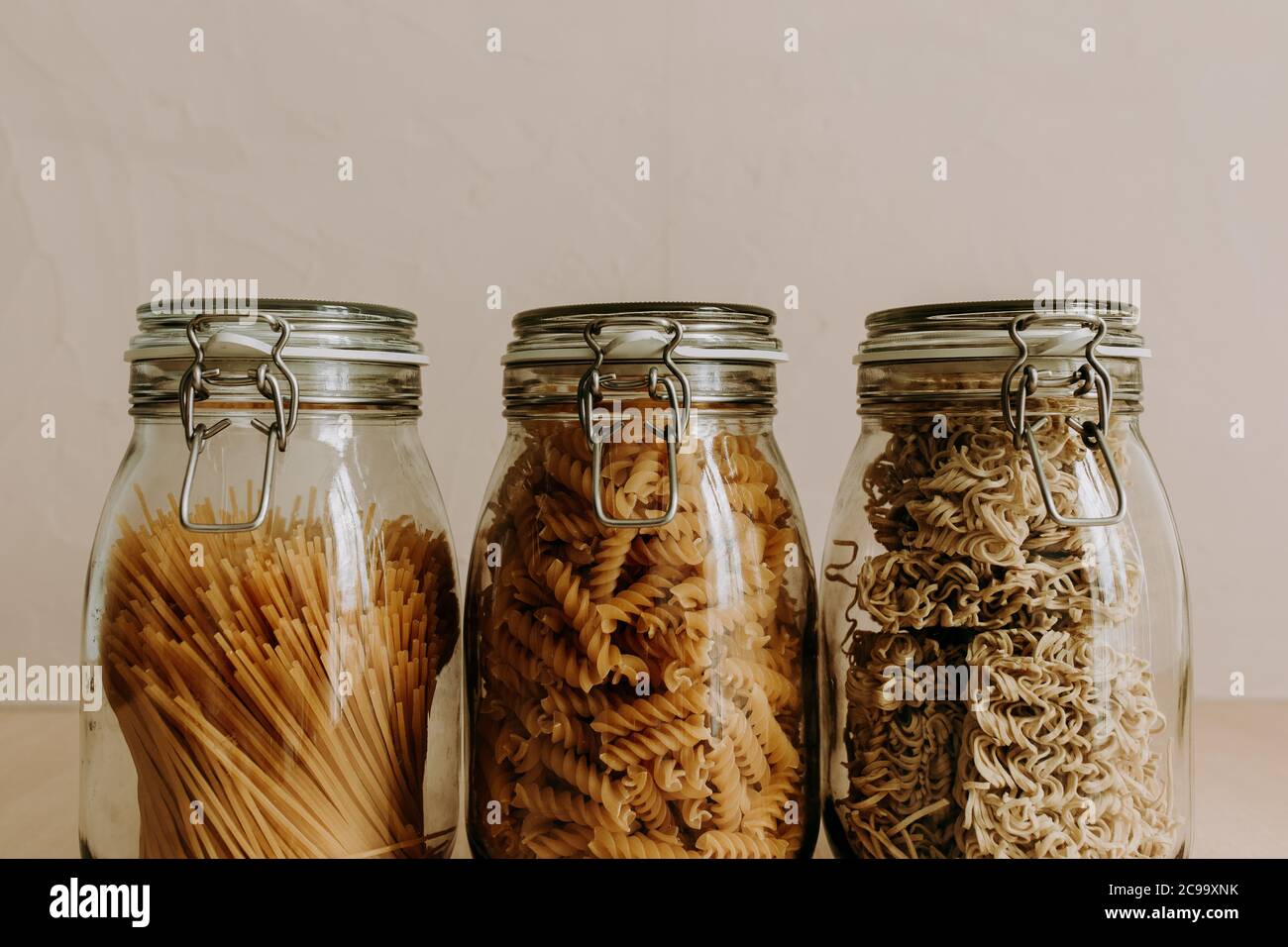 Tres recipientes de jarra de cristal llenos de ingredientes secos no cocidos. Arroz, pasta, harina, azúcar. Foto de stock
