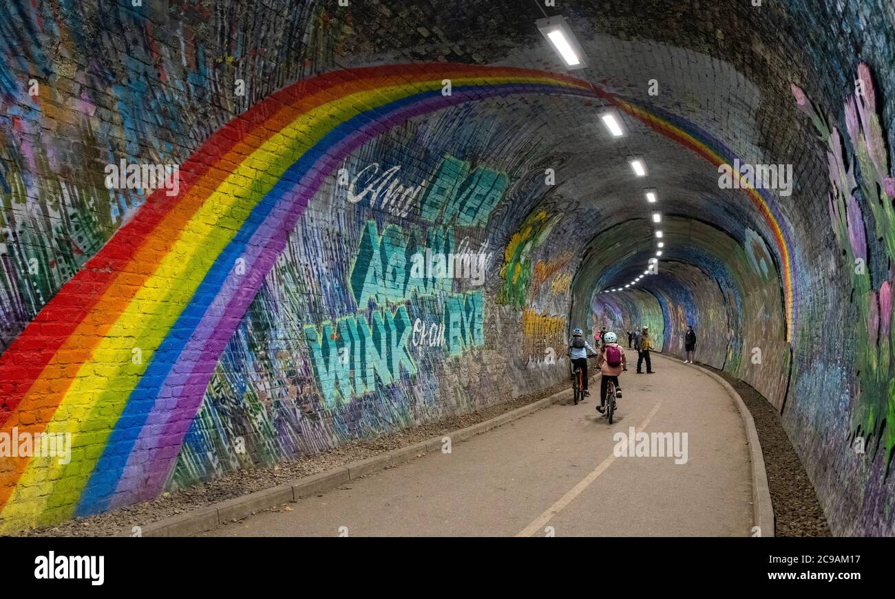 Ciclistas en el agua de Leith Walkway pasando por el mural del arco iris en el túnel de Colinton, Edimburgo, Escocia, Reino Unido Foto de stock