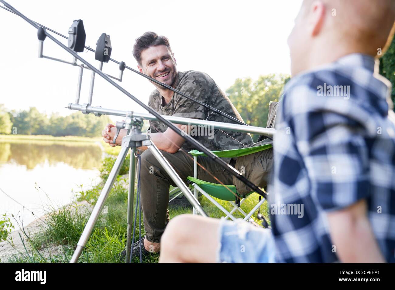 Padre e hijo pequeño charlando mientras pescan Foto de stock