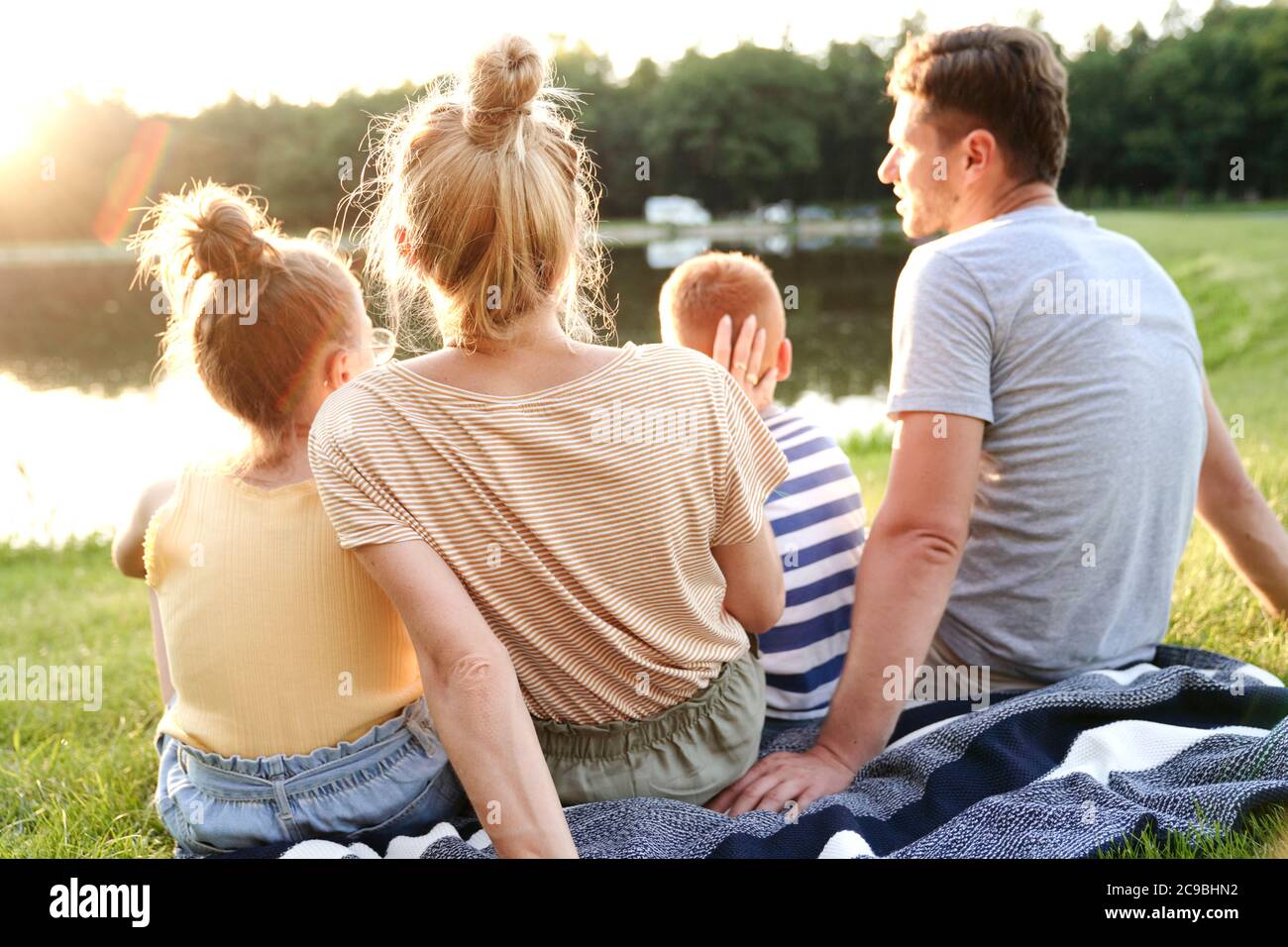 Familia viendo la puesta de sol en el lago Foto de stock